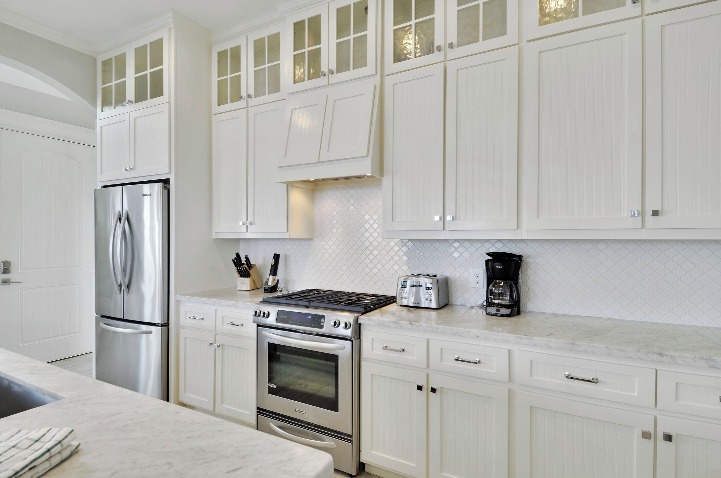 A modern kitchen with white cabinetry, stainless steel appliances, and a tiled backsplash.