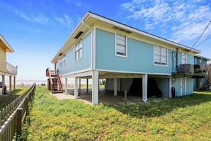 A two-story house with a covered porch, a staircase, and a view of the ocean.