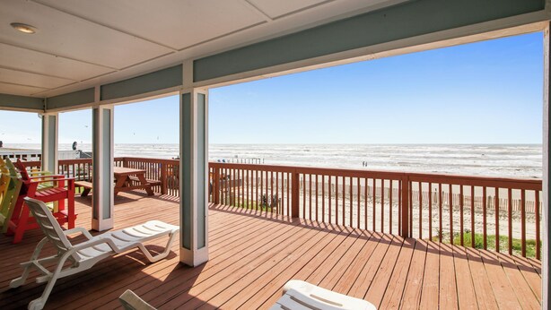 Une terrasse en bois avec des chaises longues et vue sur la plage.