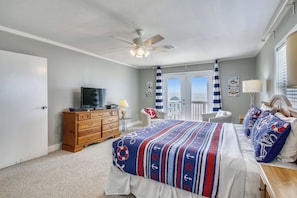 A bedroom with a bed, dresser, television, and a ceiling fan.