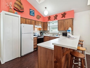 Una cucina con mobili in legno, un frigorifero bianco, un piano cottura e una grande isola con sgabelli.