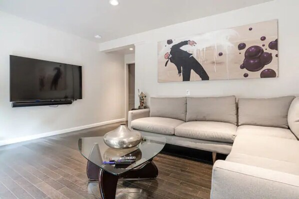 Relax in style with a large flat-screen TV, sleek coffee table, and comfortable beige sofa.
