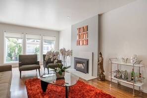 Cozy up by the fireplace in this inviting living room, featuring a comfortable armchair and a vibrant rug.
