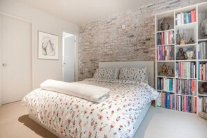 Cozy retreat with a neatly made bed and a bookshelf filled with books and decorative items.