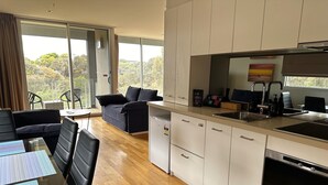 A modern kitchen with white cabinets, a built-in oven, and a large window. - Torquay285 King Studio Beachfront Resort (Torquay)