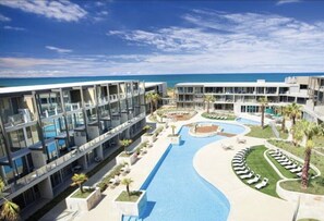 Un hôtel moderne doté d’une piscine, de nombreux balcons et offrant une vue sur l’océan.