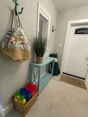 A hallway with a light blue console table, a wicker basket, a potted plant, a colorful bag, and a basket of folded blankets. - 3 blocks from Lauderdale-by-the-Sea. Great home for families. (Lauderdale-by-the-Sea)