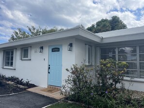 A single-story building with a light blue door, a small porch, and a tiled entrance.