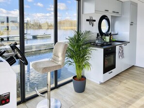 Een moderne keuken met uitzicht op een wateroppervlak, een eethoek met een stoel en een potplant.