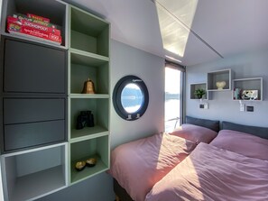 A bedroom with a bed, a window with a view, and shelves with various items.