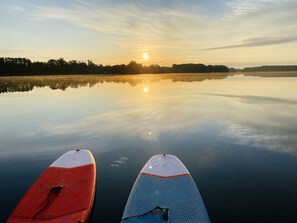 Two paddleboards on calm water with a sunset in the background.