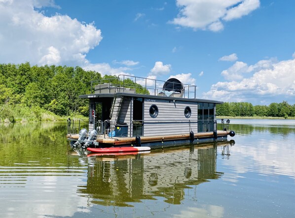 A houseboat with a covered deck, a small cabin, and a helipad.
