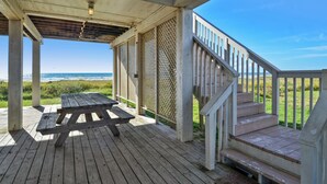 A wooden deck with a picnic table, a staircase, and a view of the ocean. - Brannen's Beachfront by Ryson Vacation Rentals (Galveston)