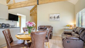 A dining area with a wooden table, brown leather chairs, and a sofa with a reclining feature. - The Ash - Arnolds Hill (Wingfield)