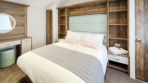 A bedroom with a bed, a dresser, a mirror, and a wardrobe.