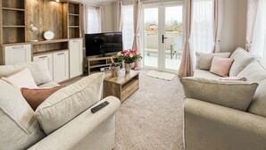 A living room with a sofa, a television, a wooden cabinet, and a sliding glass door leading to an outdoor area.
