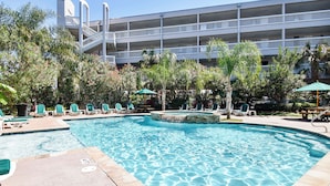 A swimming pool with lounge chairs and a building in the background. - Turtle Haven by Ryson Vacation Rentals (Galveston)