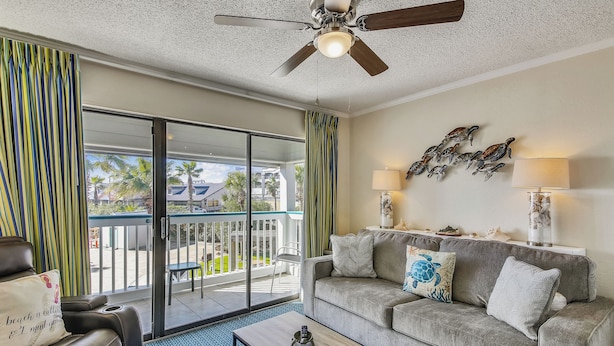 A living room with a sofa, coffee table, and a ceiling fan. - Turtle Haven by Ryson Vacation Rentals (Galveston)