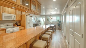Una cucina moderna con mobili in legno, un piano di lavoro in granito e un'isola centrale con sgabelli.