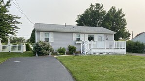 Ein zweistöckiges Haus mit Veranda, Auffahrt und gepflegtem Rasen.