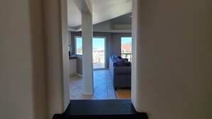 A hallway leading to a living area with a sofa and a view of the outside. - Lovely 2 Bdrm apartment with private terrace with grill (Tijuana)