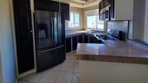 A modern kitchen with black cabinets, stainless steel appliances, and a large island. - Lovely 2 Bdrm apartment with private terrace with grill (Tijuana)