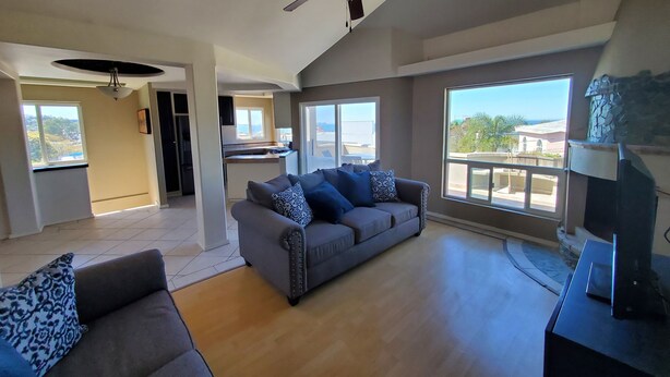 A spacious living area with a grey sofa, a ceiling fan, and a view of the outside. - Lovely 2 Bdrm apartment with private terrace with grill (Tijuana)