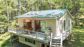 Una cabaña con terraza, comedor y cocina.