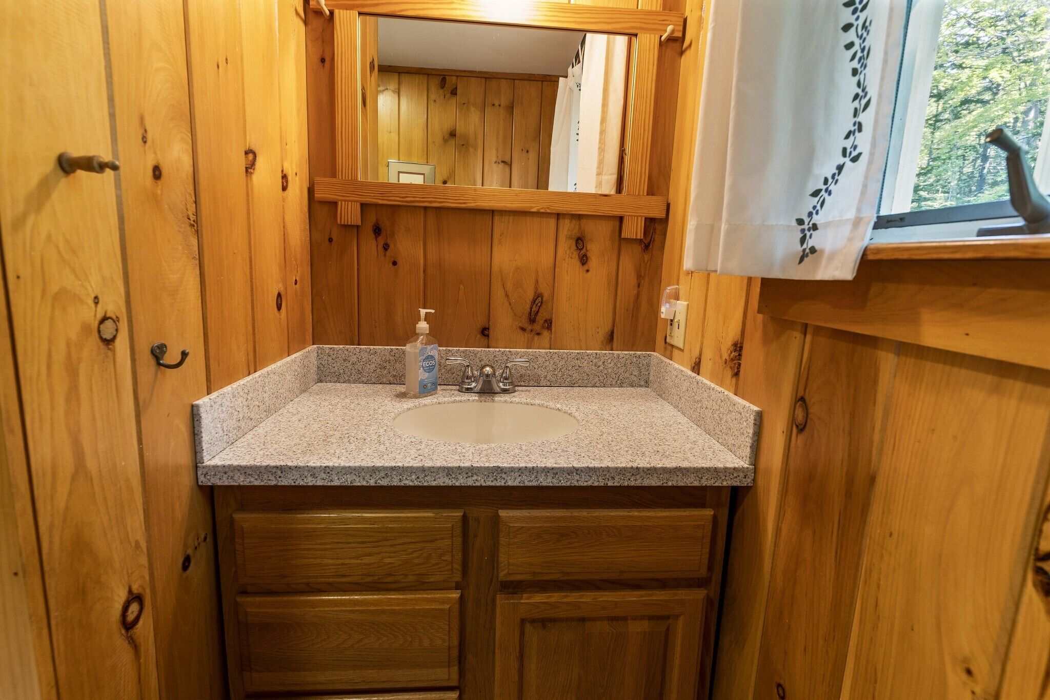 A wooden bathroom with a granite countertop sink, a mirror, and wooden cabinets.