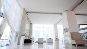 A spacious living area with a high ceiling, large windows, and a modern interior design.