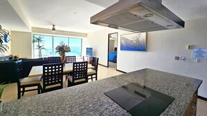 A modern kitchen with granite countertops, a central island, and a large overhead vent.