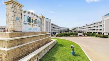 A hotel entrance with a sign for 'Casa de Mar Suites & Rentals' and a large building in the background.