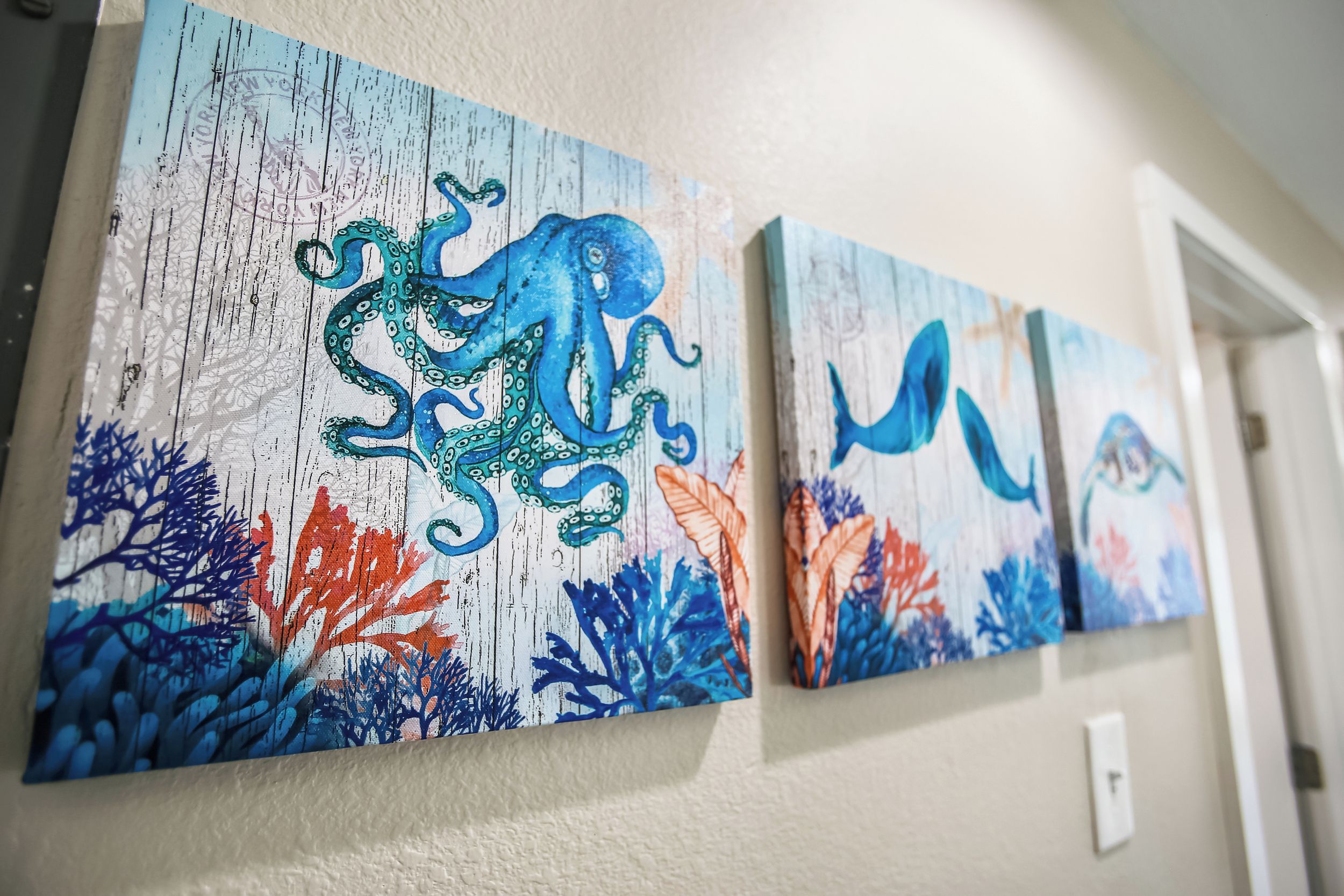 Three paintings of an octopus on a wall.