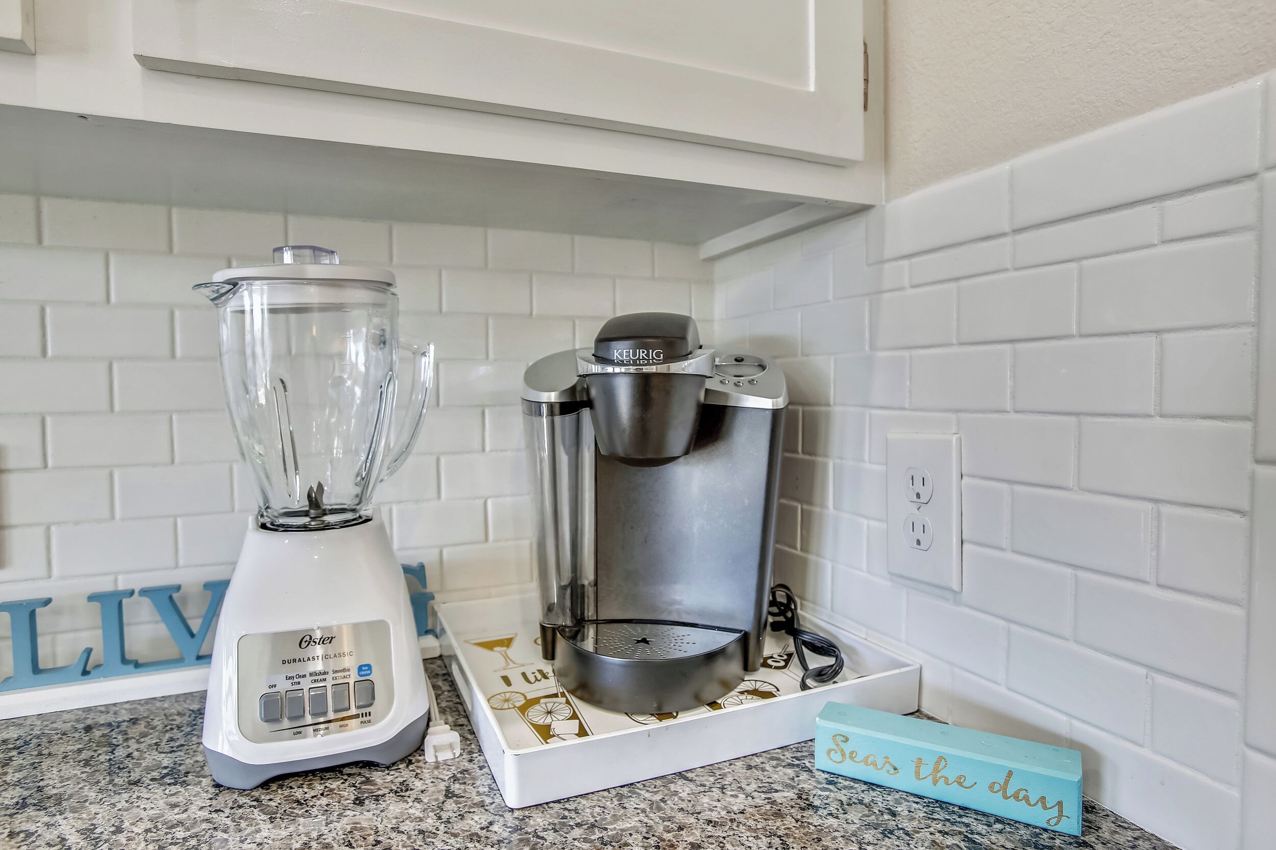 A kitchen with a white countertop, a blender, and a coffee maker.