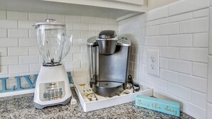 A kitchen with a white countertop, a blender, and a coffee maker.