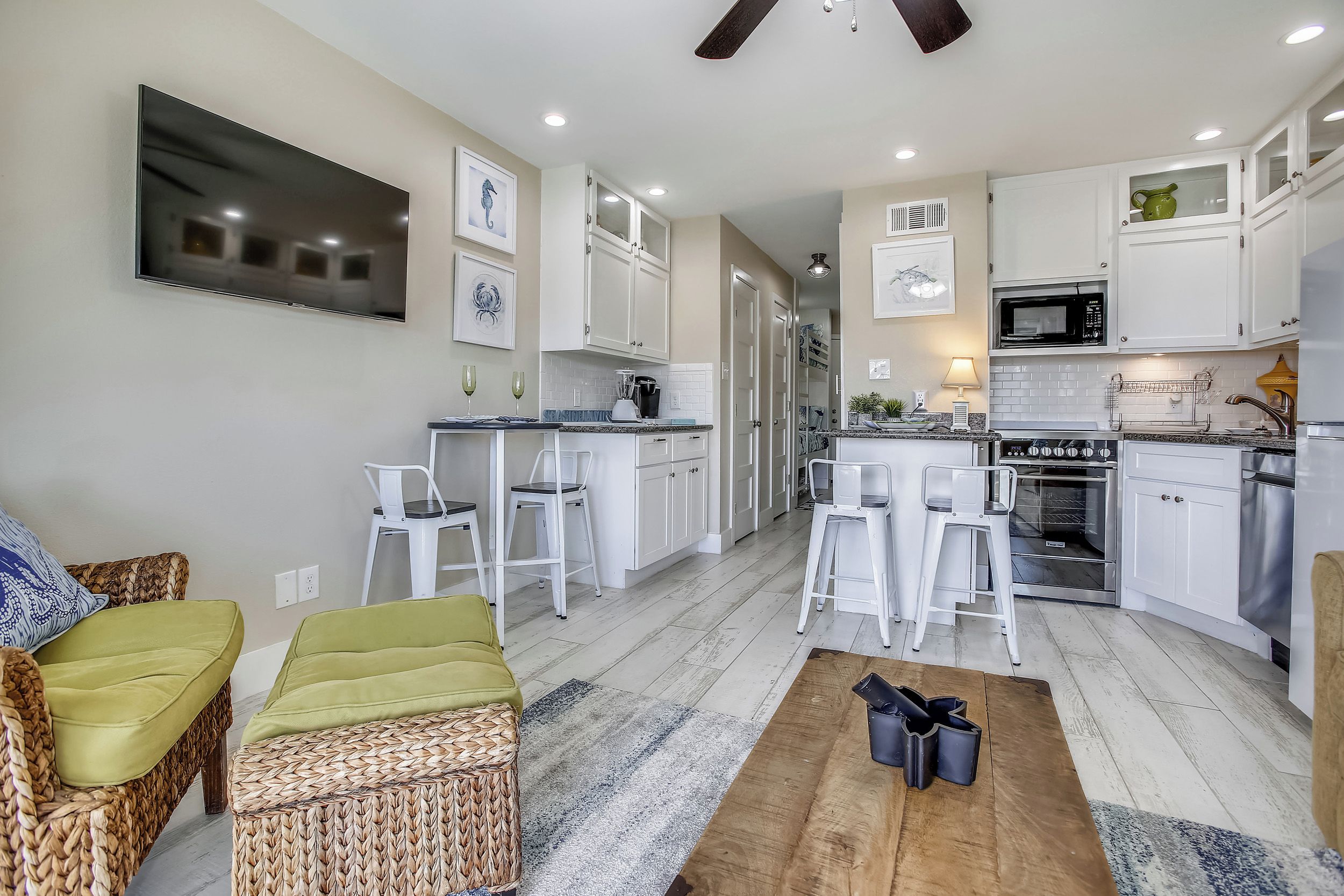 A modern kitchen with white cabinets, a microwave, and an oven. There is a dining area with a table and chairs.