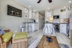 Una cocina moderna con armarios blancos, un microondas y una estufa. Hay un comedor con una mesa y sillas.