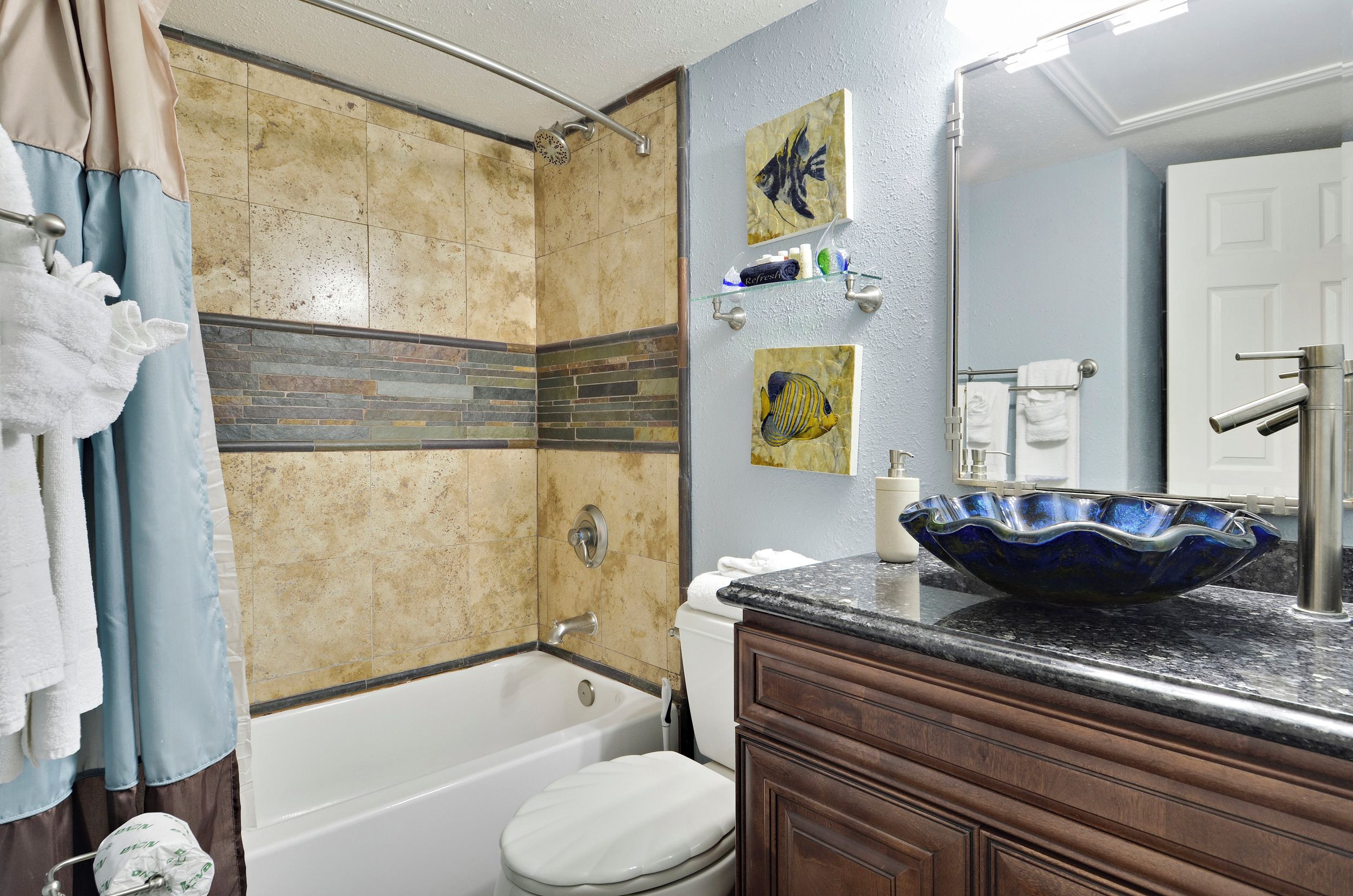 Un baño con bañera, inodoro y lavabo. Hay toallas colgadas en un perchero y una cortina de ducha.