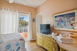 A hotel room with a bed, a television, a dresser, and a painting on the wall.