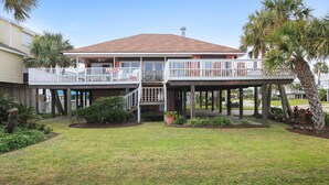 A two-story house with a covered porch and a balcony on each floor. - Casa Rosa West by Ryson Vacation Rentals (Galveston)