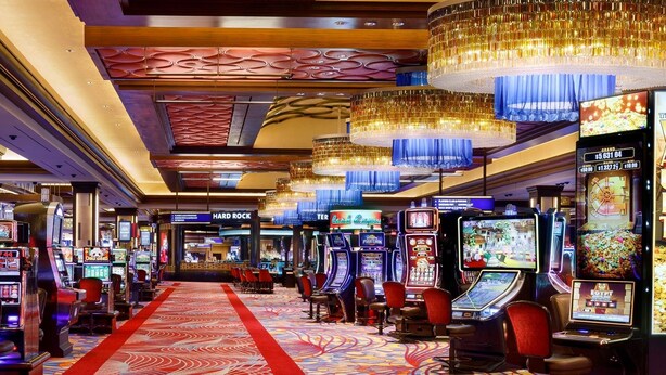 Una sala da gioco con slot machine, tappeto rosso e lampadari moderni.