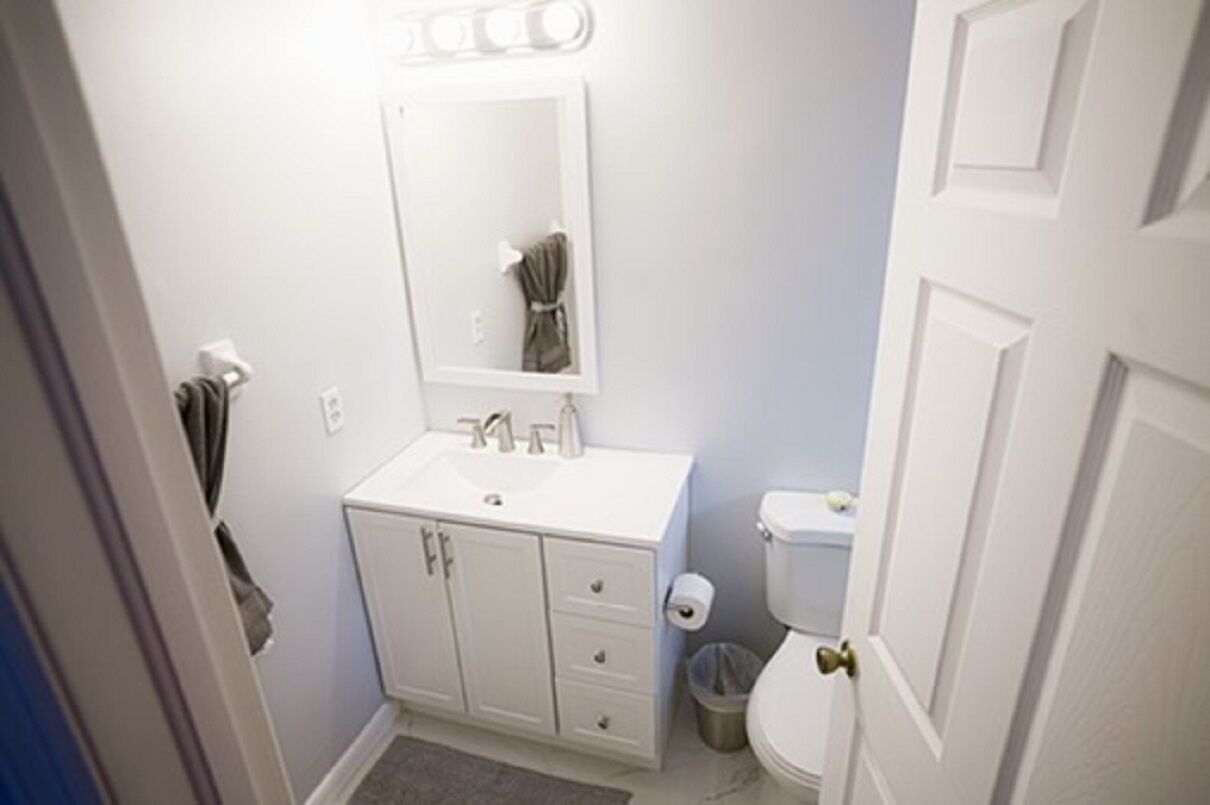 A small, white bathroom with a sink, mirror, and toilet.