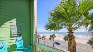 Un porche verde con vistas a la playa y al océano.