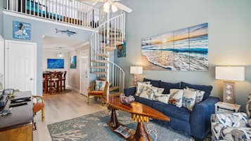 Ein geräumiges Wohnzimmer mit einem blauen Sofa, einem Holztisch und einer Wendeltreppe.