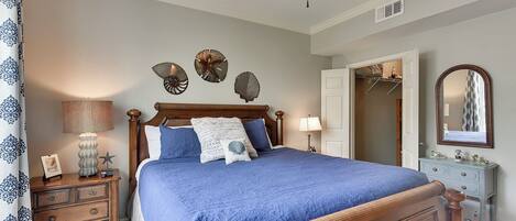A bedroom with a wooden bed, a ceiling fan, a dresser, a mirror, and wall decorations.