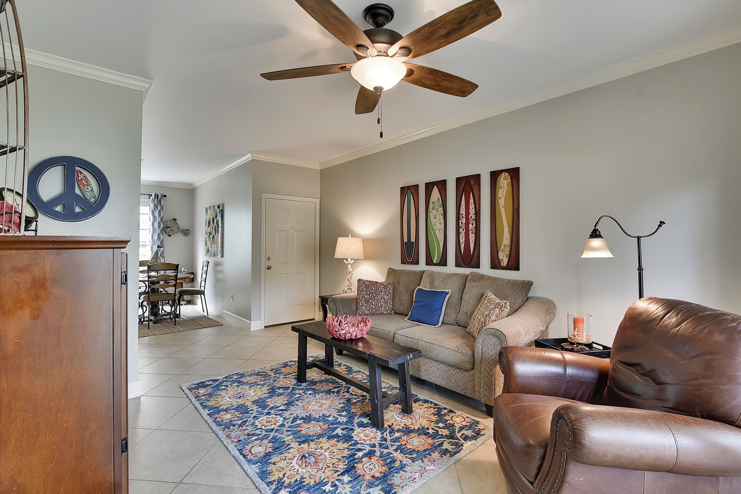 A living room with a ceiling fan, a sofa, a coffee table, and a patterned rug.