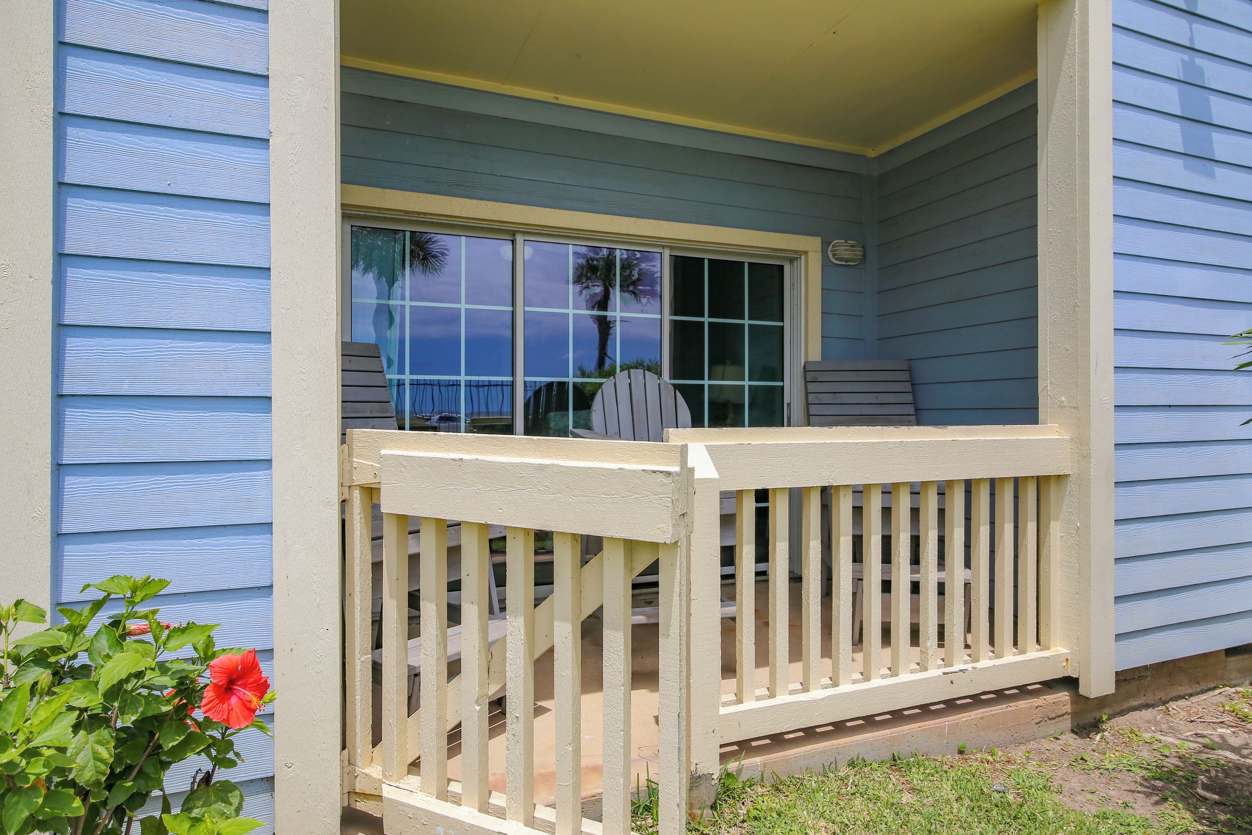 A porch with a white railing, a window, and a view of the sky.