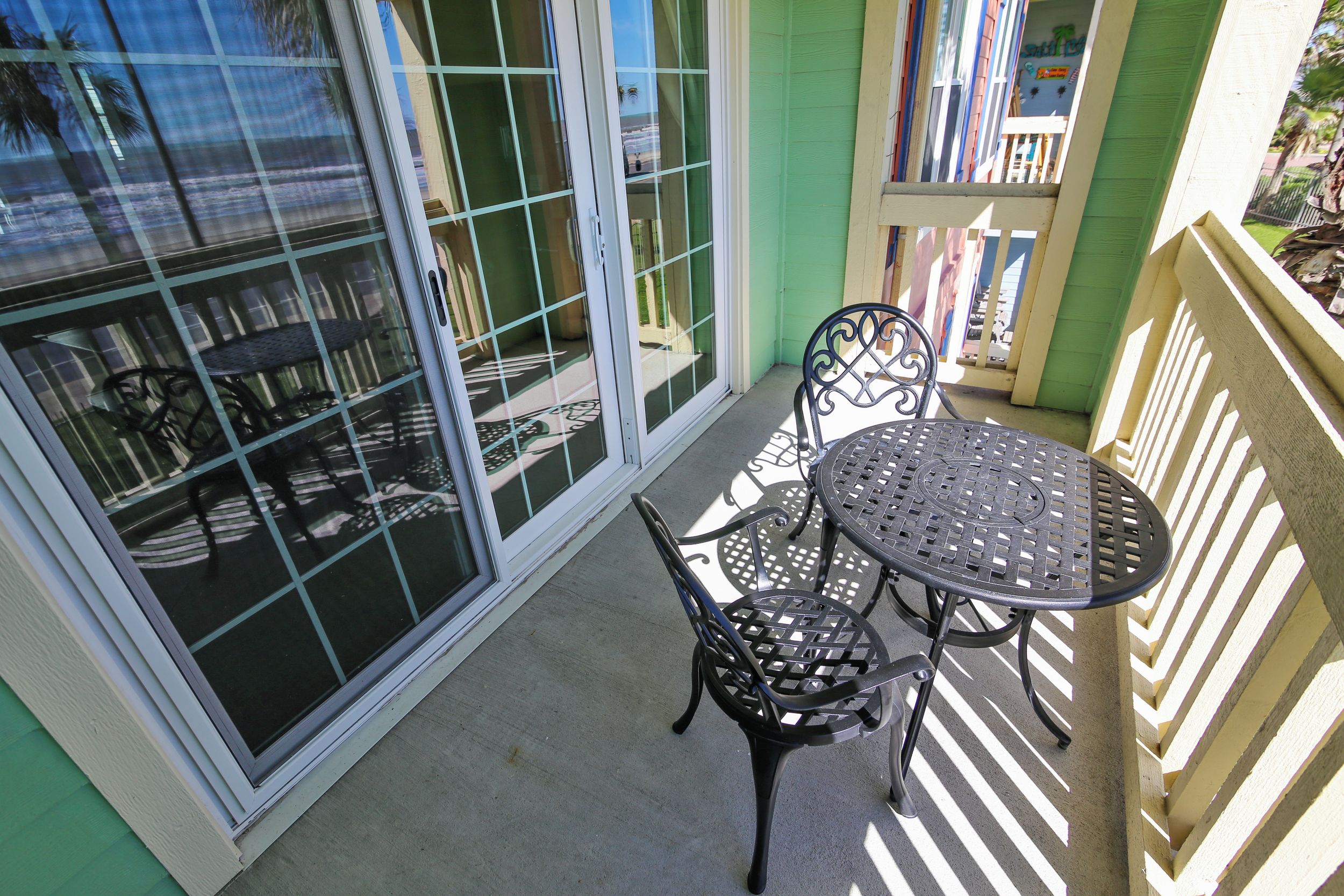 Un balcon avec une table et des chaises, une porte-fenêtre coulissante et une vue sur la plage.