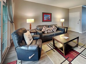 A living room with a leather sofa, two side tables with lamps, a coffee table, and a patterned rug.