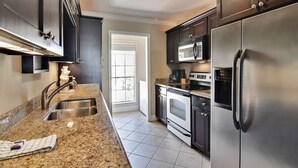 A modern kitchen with stainless steel appliances, granite countertops, and dark cabinetry. - Dawn 631 by Ryson Vacation Rentals (Galveston)